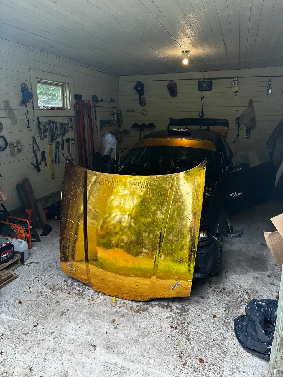 Kultainen konepelti BMW E36:ssa pienessä puutallissa